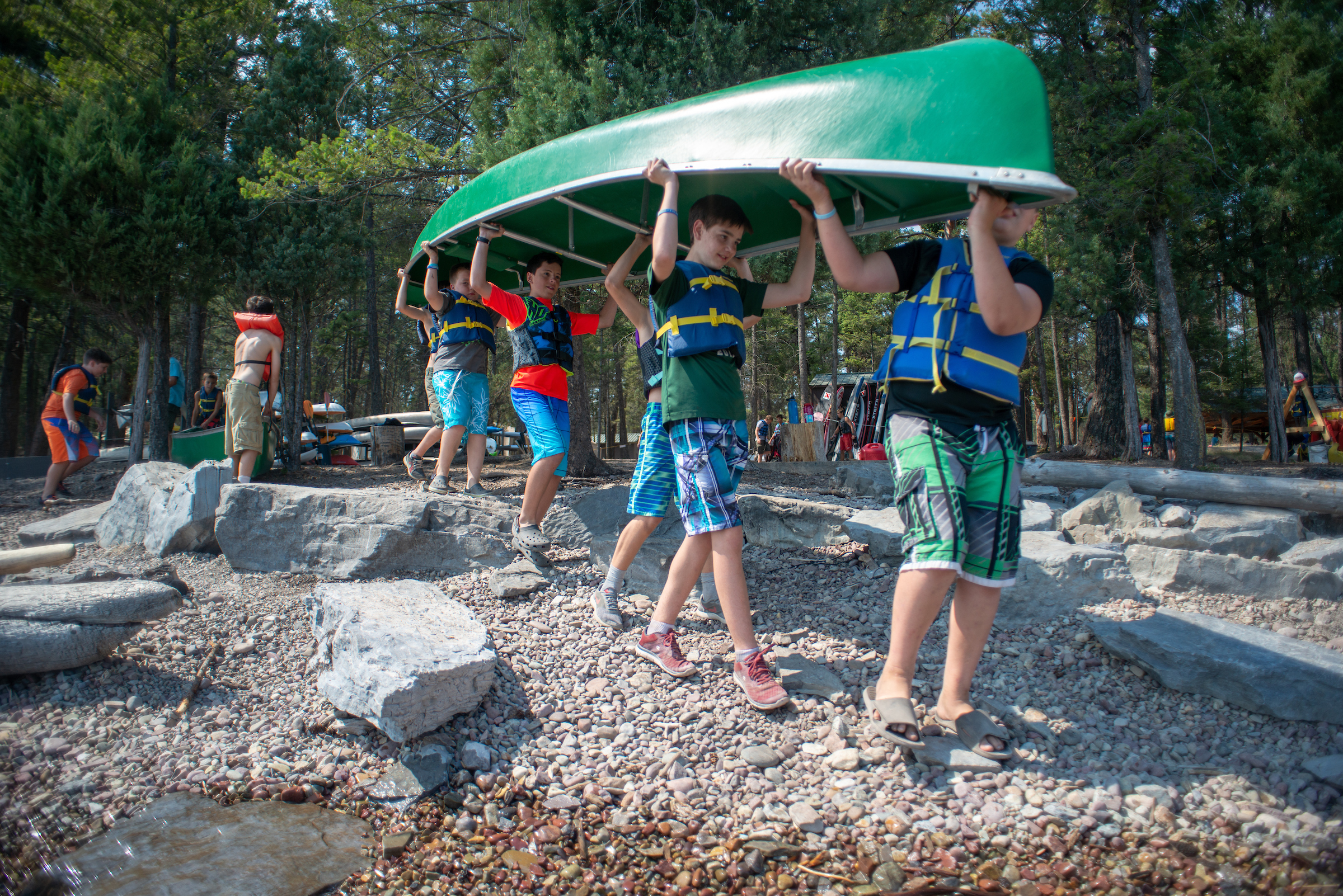 Several Boy Scouts carry a canoe to a lake at summer camp in Montana.