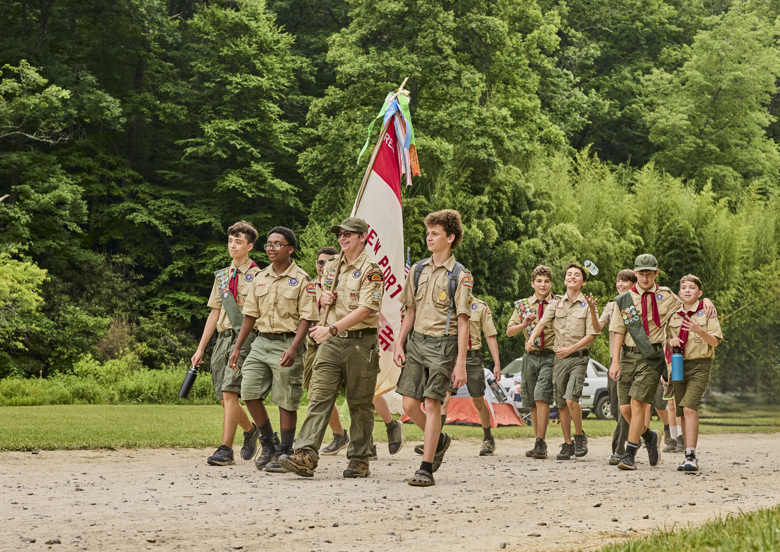 Scouts BSA troop walking along a trail carrying a flag.