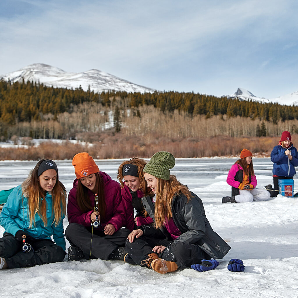 Girls on an outdoor adventure, ice fishing on a lake. 