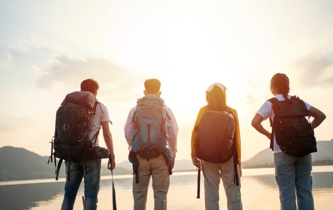 A group of Asian friends backpacking bag and walking for picnic and camping near lake