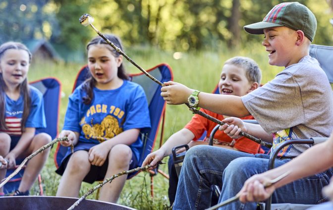 Cub Scouts sitting around a campfire making and eating s'mores